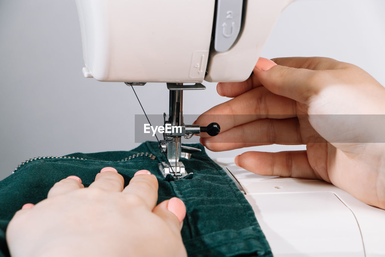 Cropped hands of woman using sewing machine