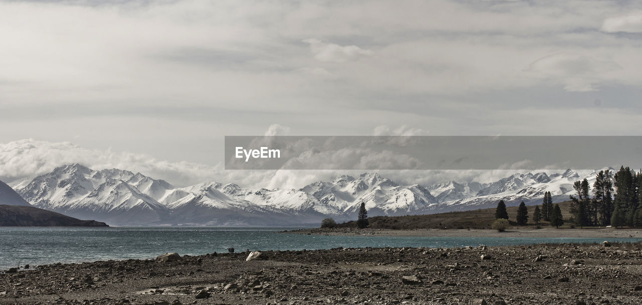 Scenic view of sea by mountains against sky