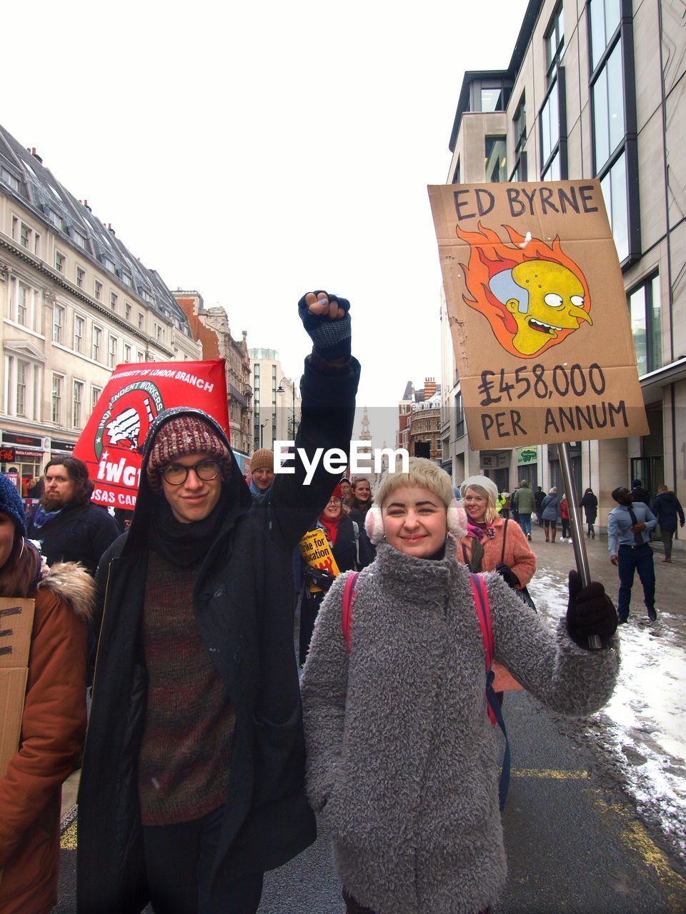 PEOPLE STANDING ON STREET AGAINST SKY