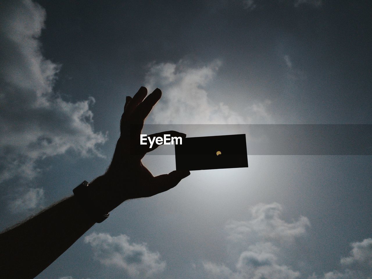 Low angle view of person hand against sky during eclipse 