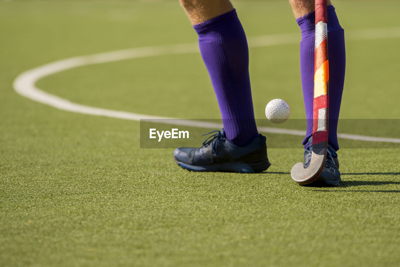 Low section of man playing hockey on field