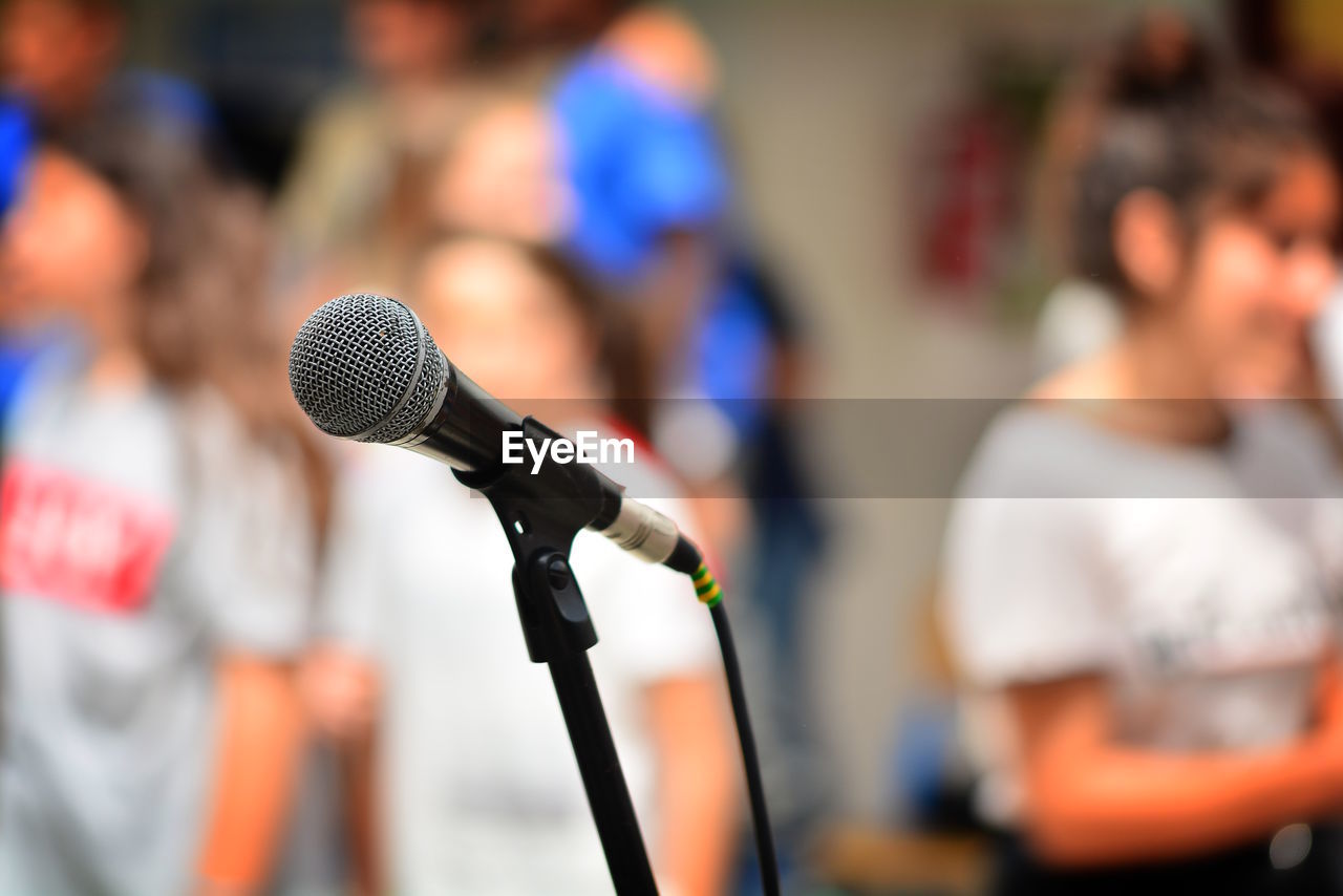 Close-up of microphone on stand against people