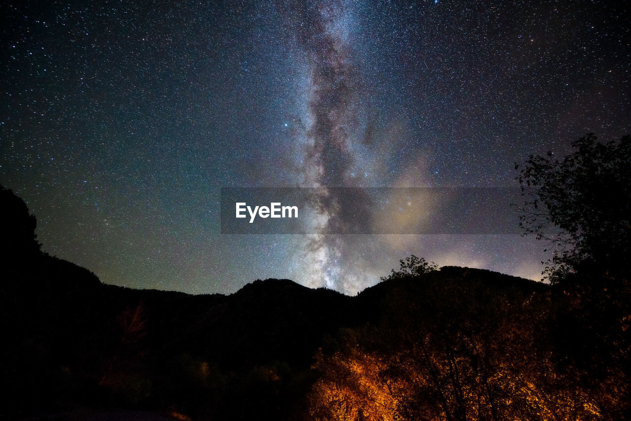 Scenic view of silhouette mountain against milky way at night