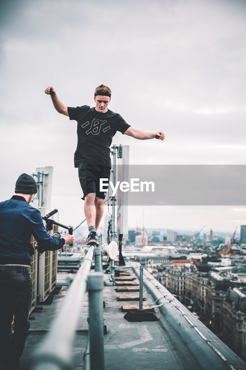 YOUNG MAN WITH ARMS OUTSTRETCHED AGAINST SKY