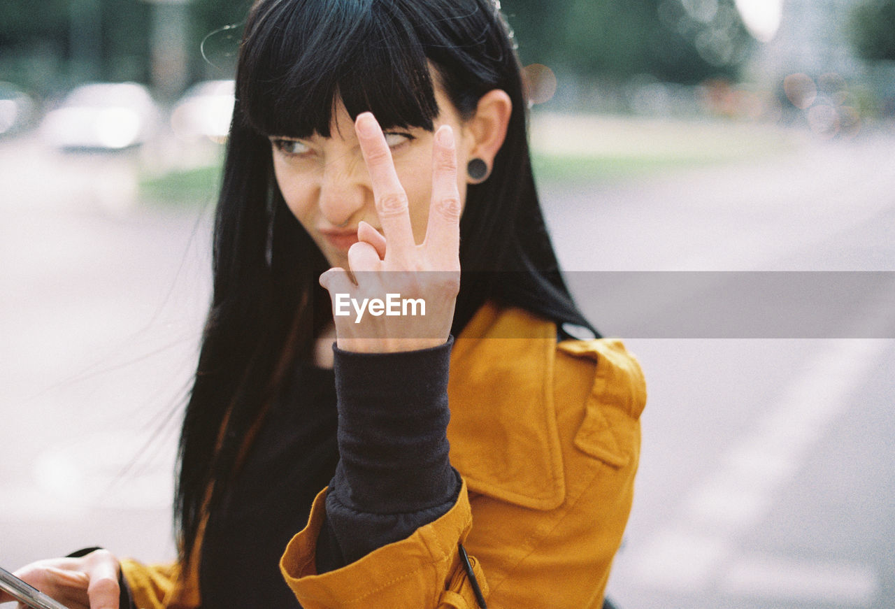 Close-up of young woman gesturing outdoors