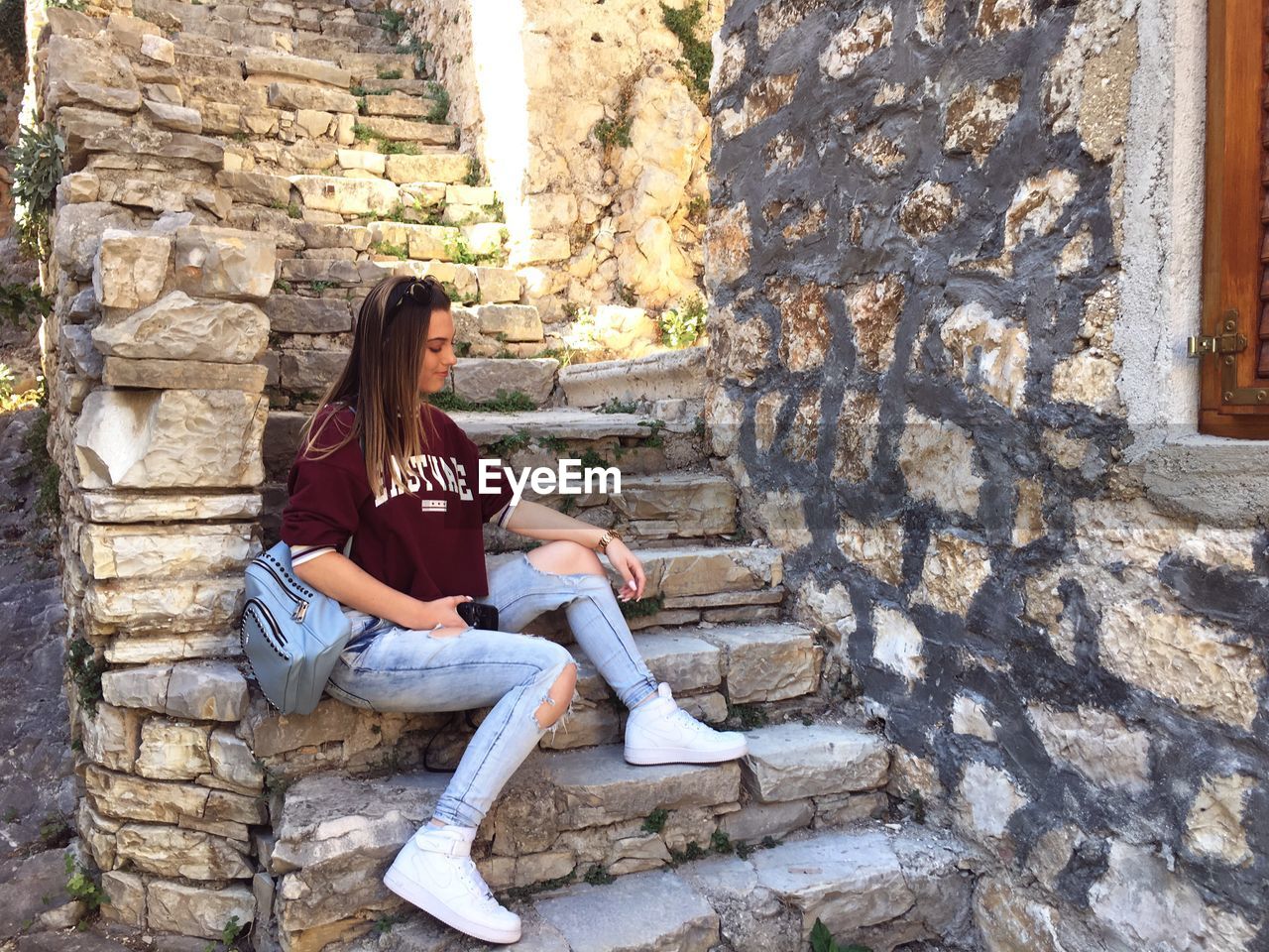 FULL LENGTH OF WOMAN SITTING ON WALL