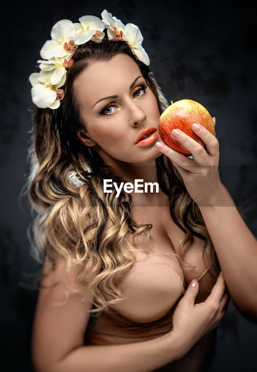 Close-up portrait of seductive woman holding apple