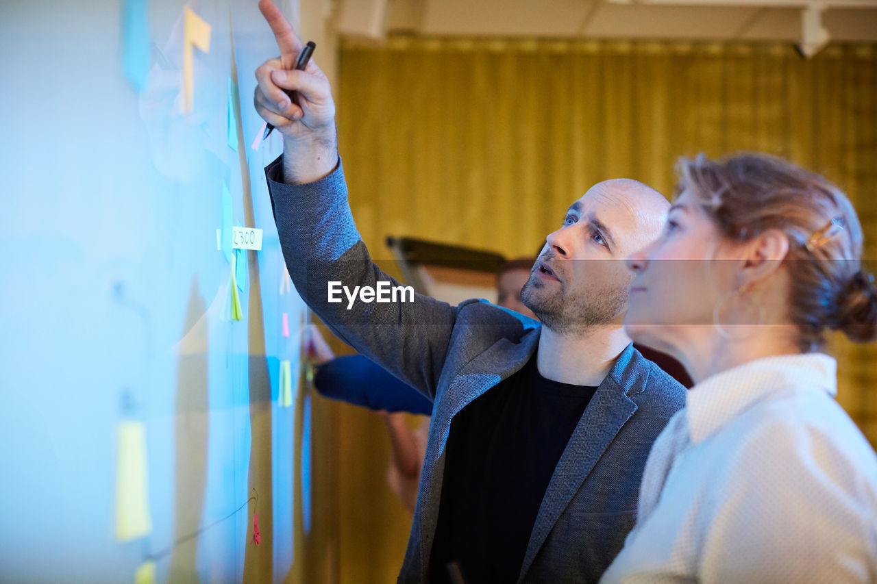 Entrepreneur pointing while standing by businesswoman in office workshop