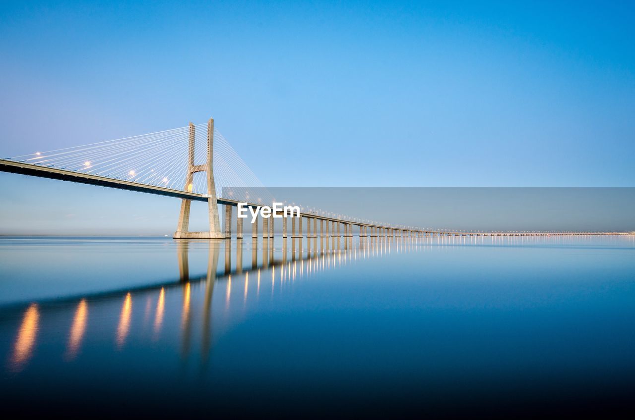 Bridge over sea against clear blue sky