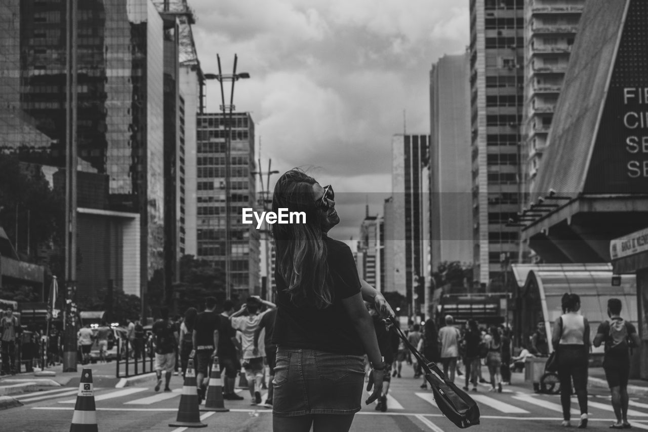 WOMAN WALKING ON ROAD IN CITY