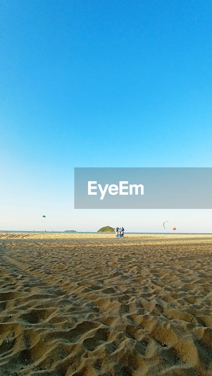 Scenic view of beach against clear blue sky