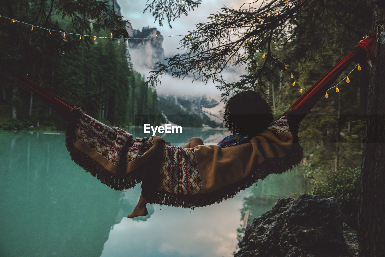 Young woman resting in hammock against lake