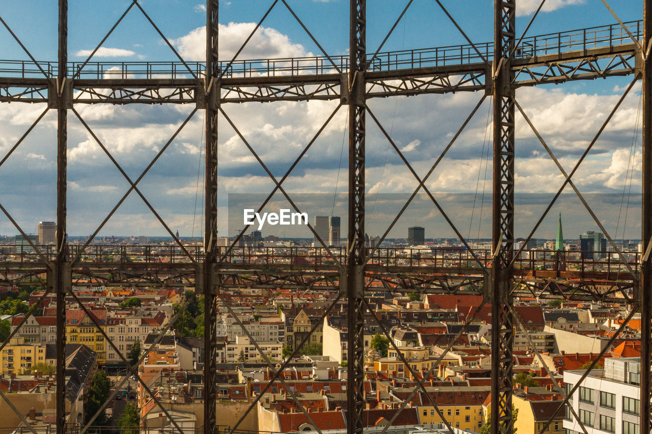 VIEW OF CITYSCAPE AGAINST SKY SEEN THROUGH METAL BRIDGE