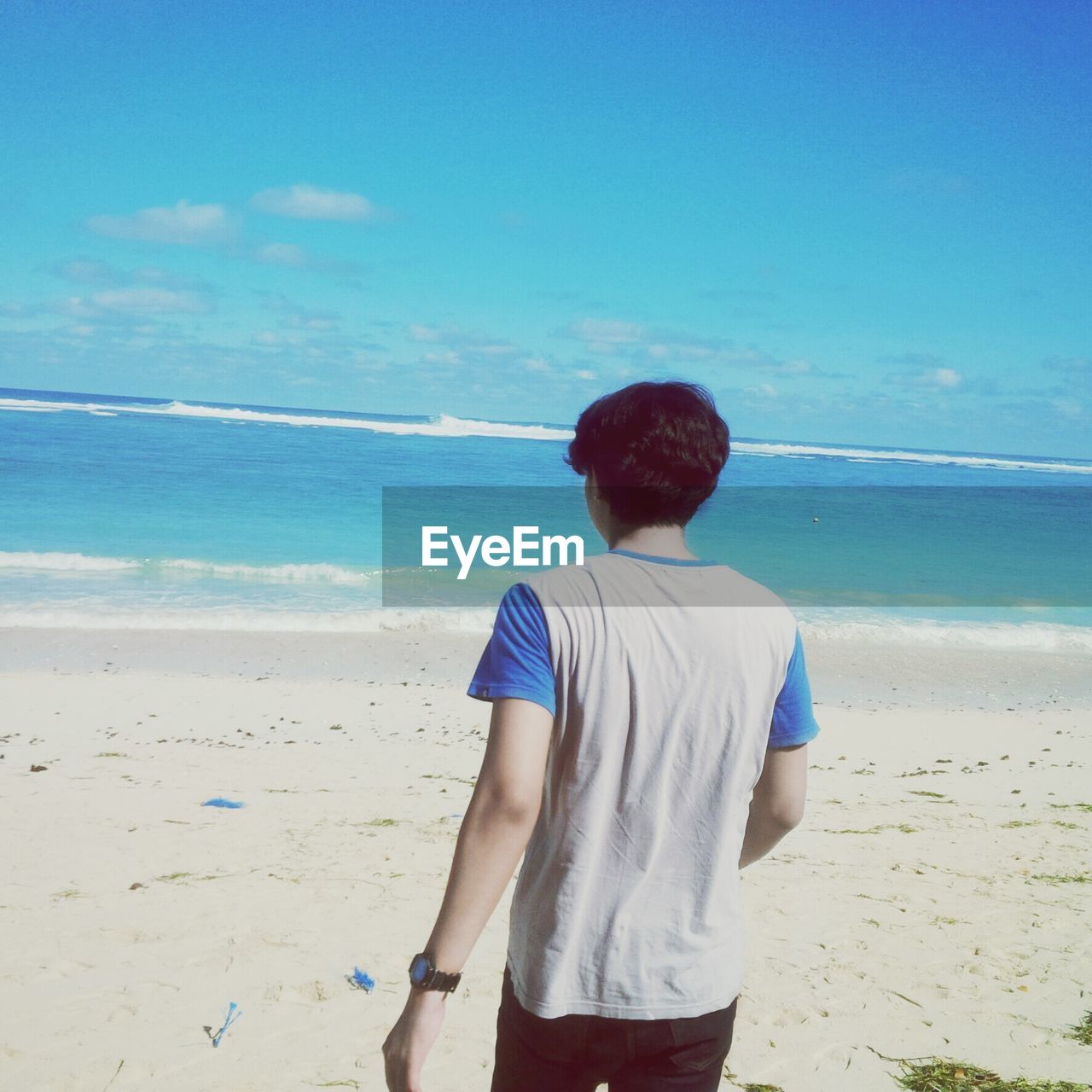 REAR VIEW OF WOMAN STANDING ON BEACH