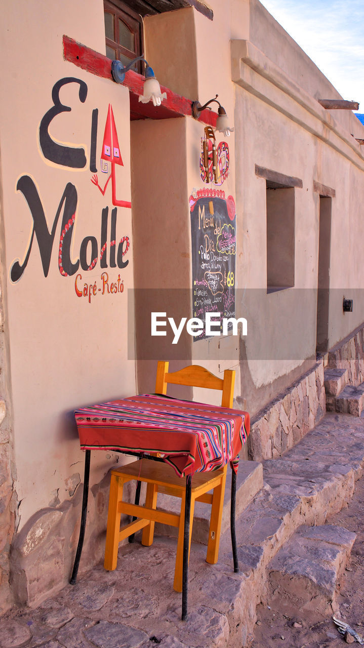 EMPTY CHAIRS AND TABLE AGAINST WALL IN BUILDING