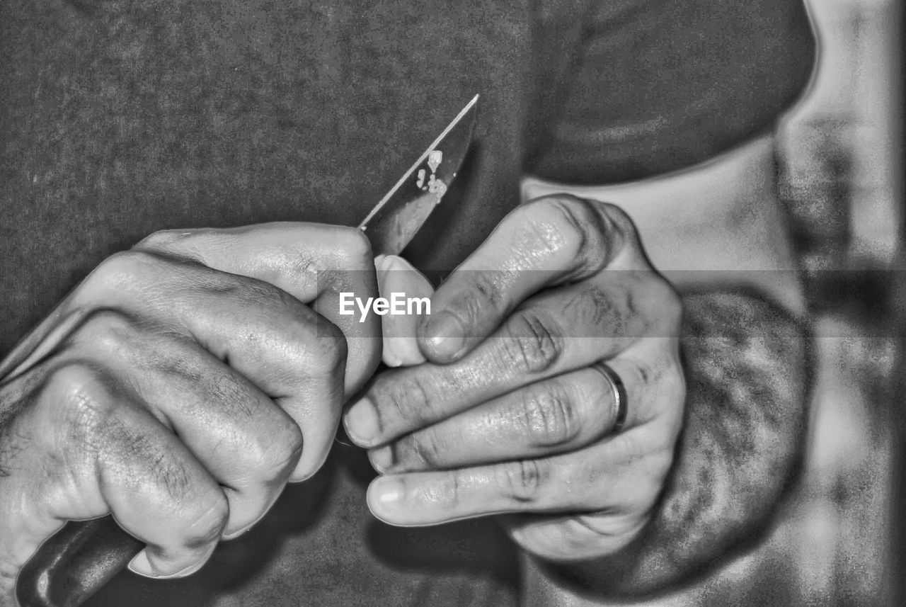 Close-up midsection of man cutting food with knife