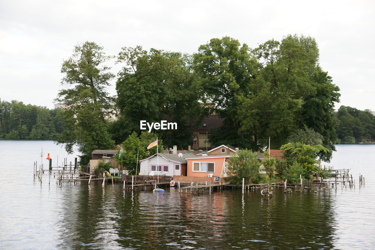 Stilt houses amidst river against sky