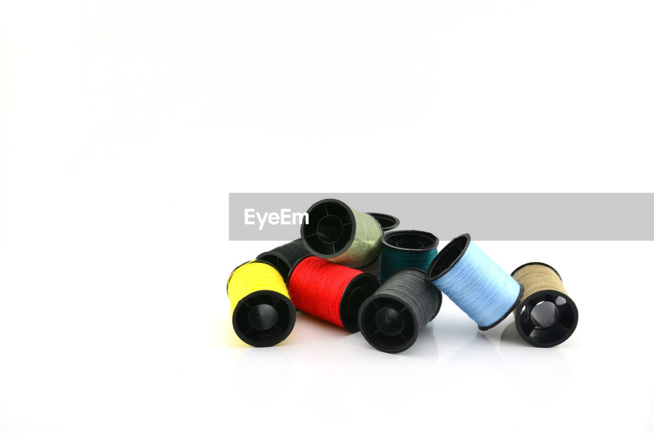 Close-up of multi colored thread spools against white background