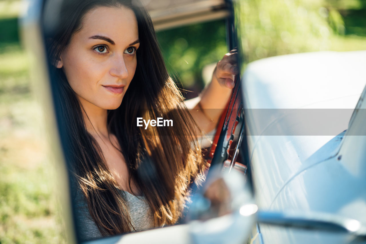 Reflection of thoughtful woman on side-view mirror