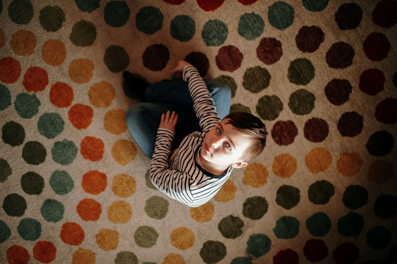 High angle portrait of boy sitting on bed