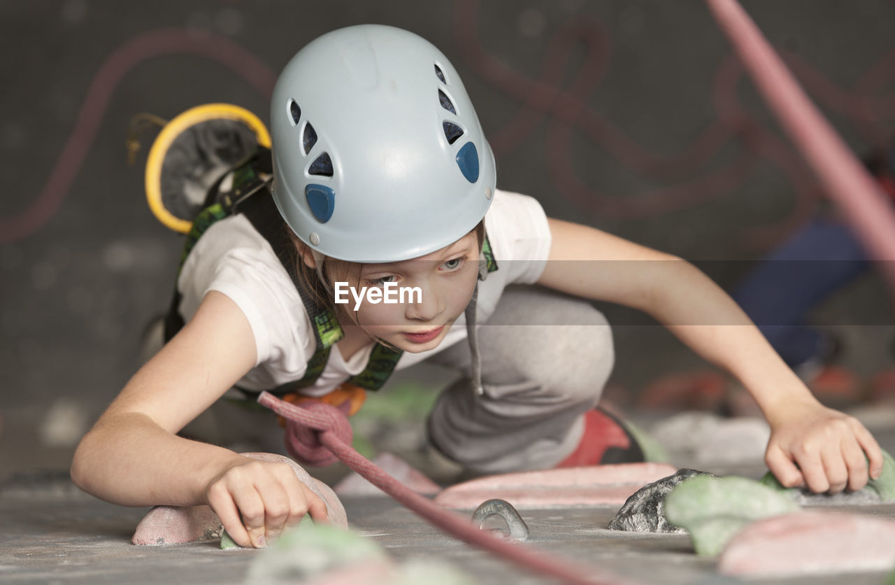 Young girl climbing at indoor climbing wall in england / uk