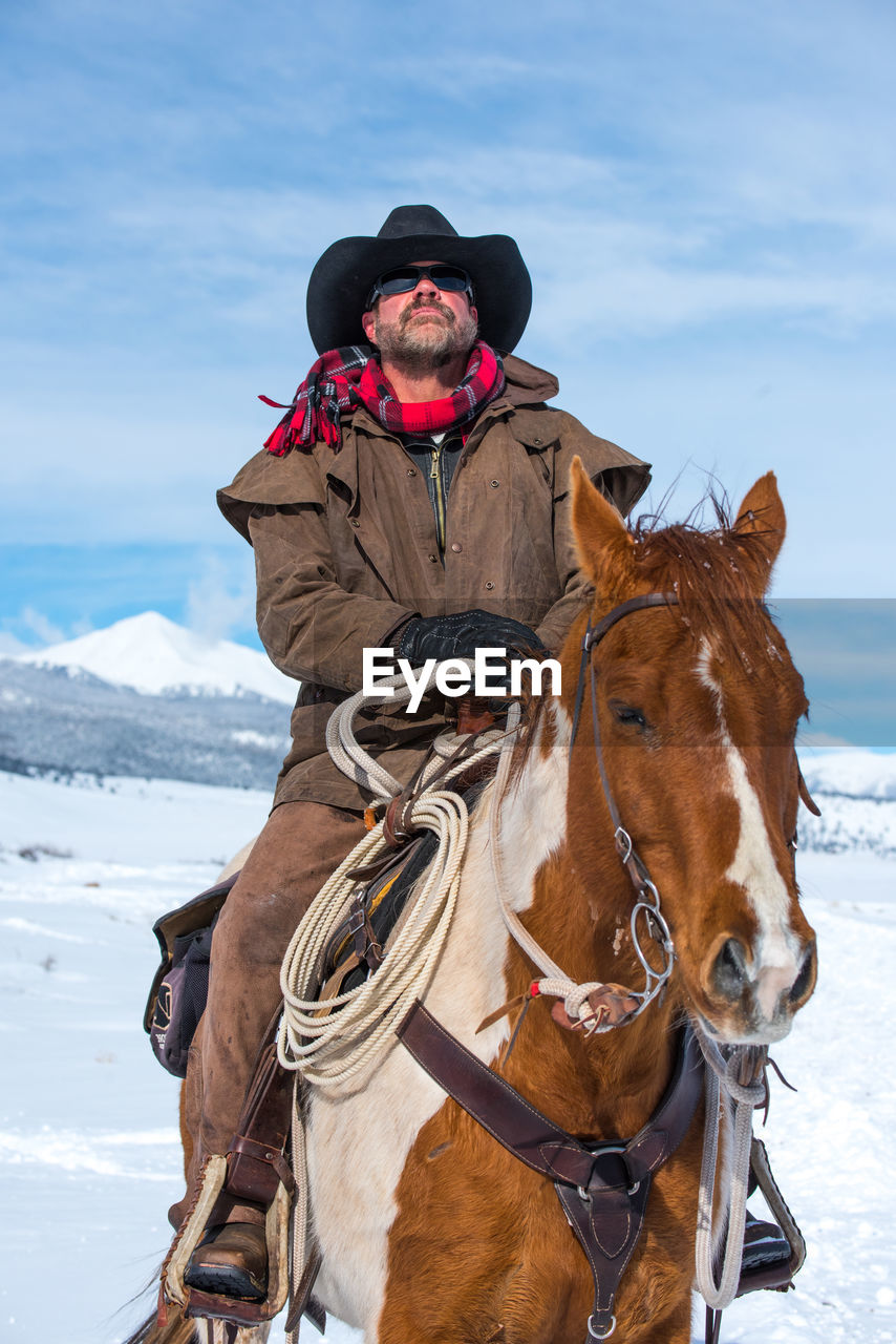 Man riding horse in snow against sky