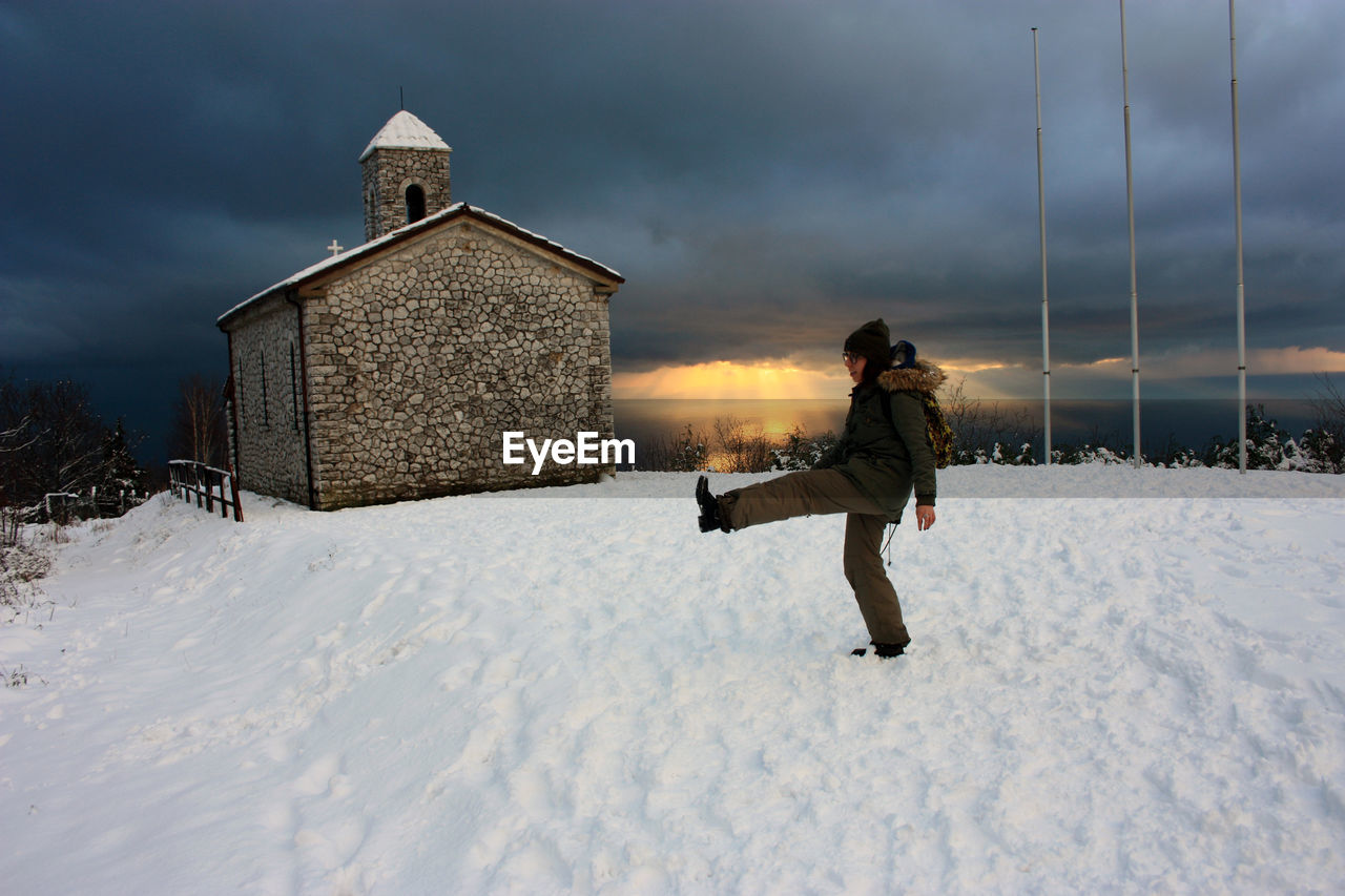 FULL LENGTH OF MAN ON SNOW COVERED LAND AGAINST SKY