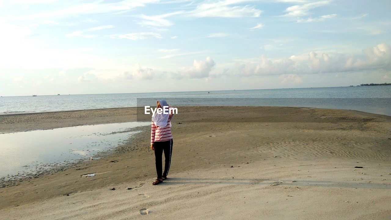 Woman walking at beach against sky