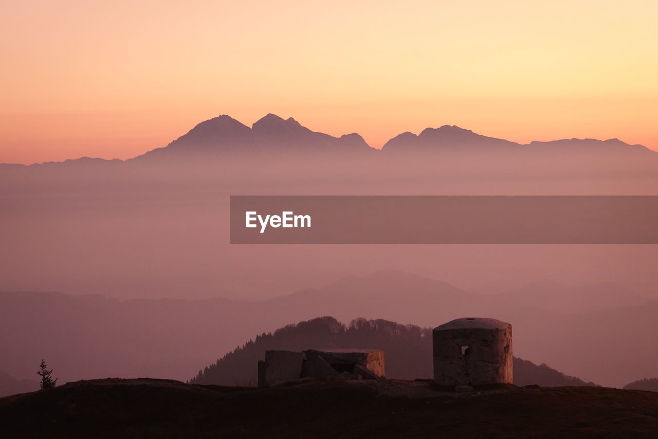 Scenic view of silhouette mountains against orange sky