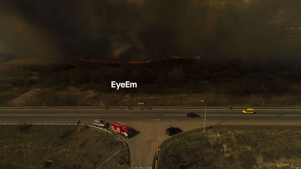 Massive fire, dry grass lanes in fire, firefighters at work, disaster, ecological catastrophe