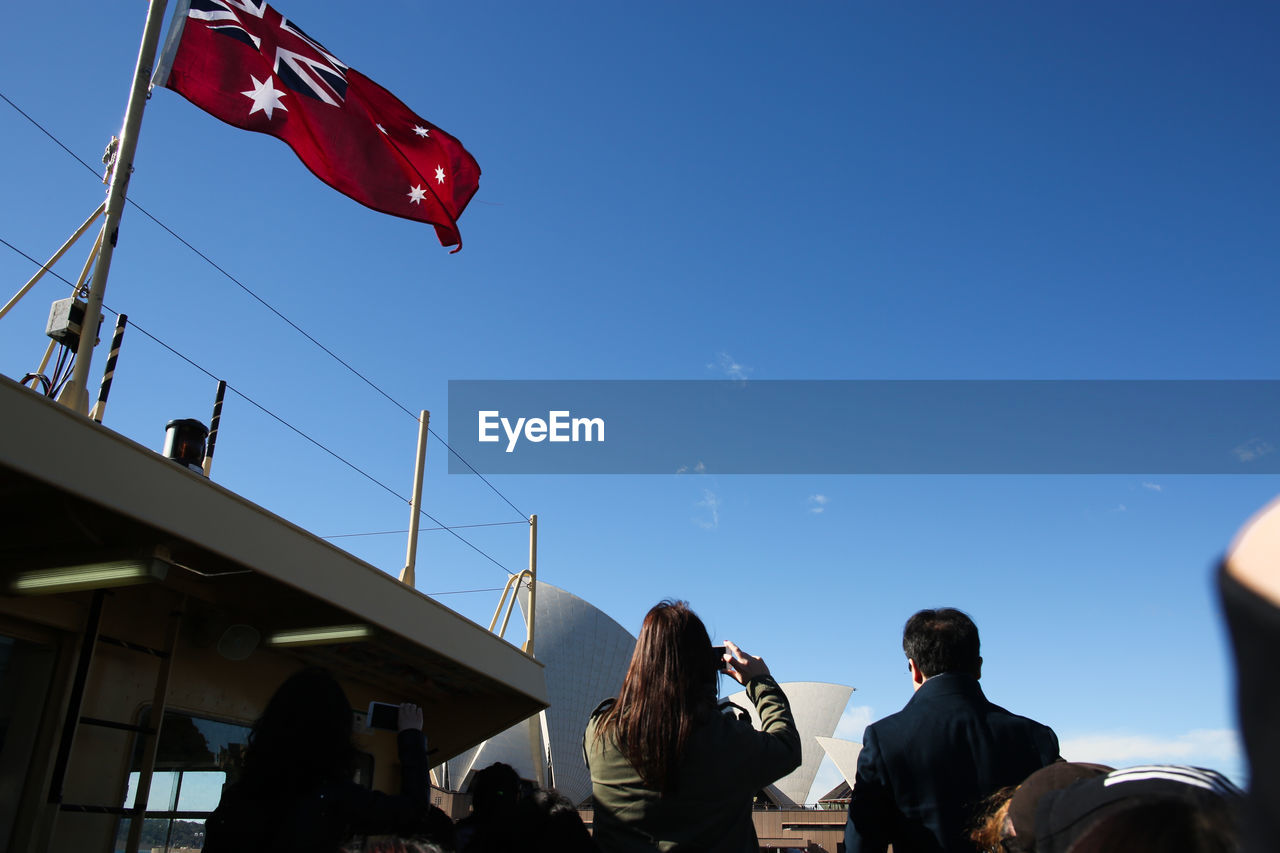 Rear view of people by sydney opera house in city