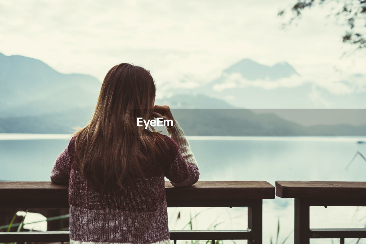 Rear view of woman looking at sea against sky during winter