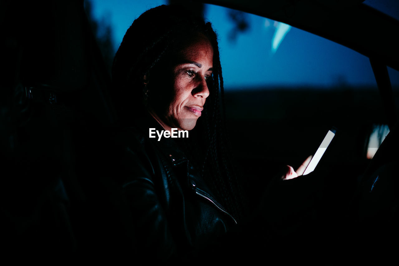 Woman using smart phone while sitting in car