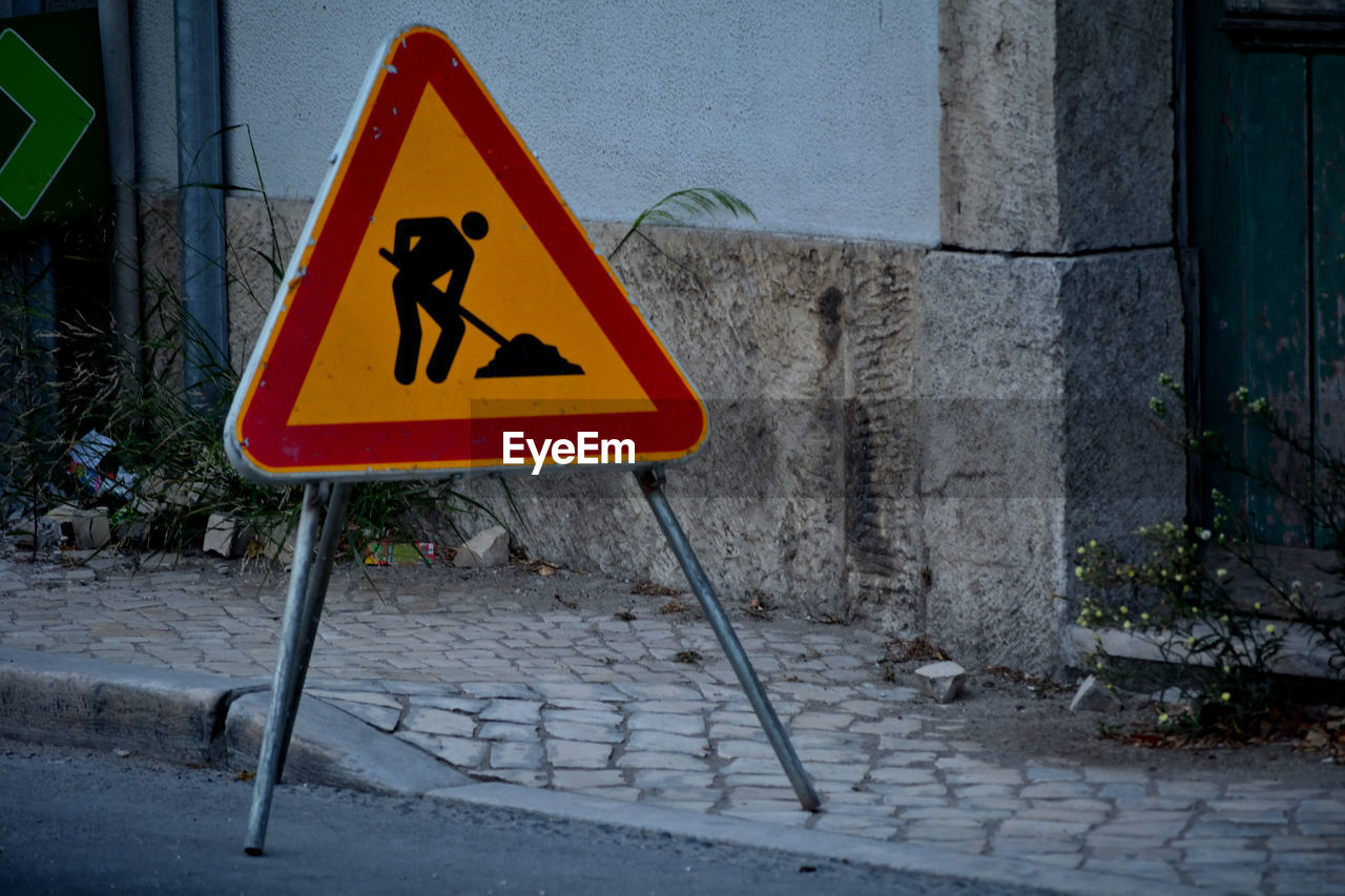 sign, communication, road, warning sign, triangle shape, representation, road sign, yellow, lane, signage, traffic sign, street, human representation, guidance, no people, city, shape, urban area, street sign, day, red, infrastructure, warning symbol, information sign, protection, outdoors, security, architecture, transportation, bird