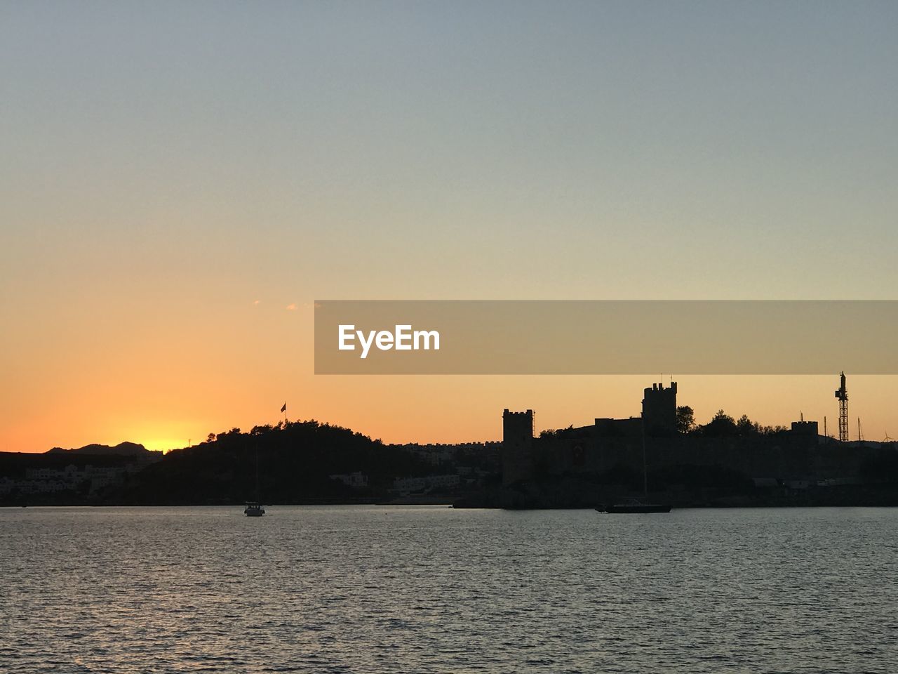 SILHOUETTE BUILDINGS AND SEA AGAINST SKY DURING SUNSET