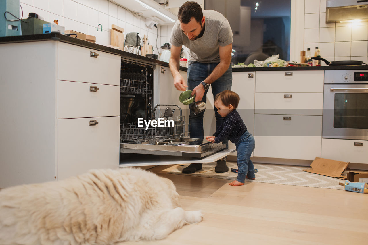 Father with toddler putting dishes into dishwasher