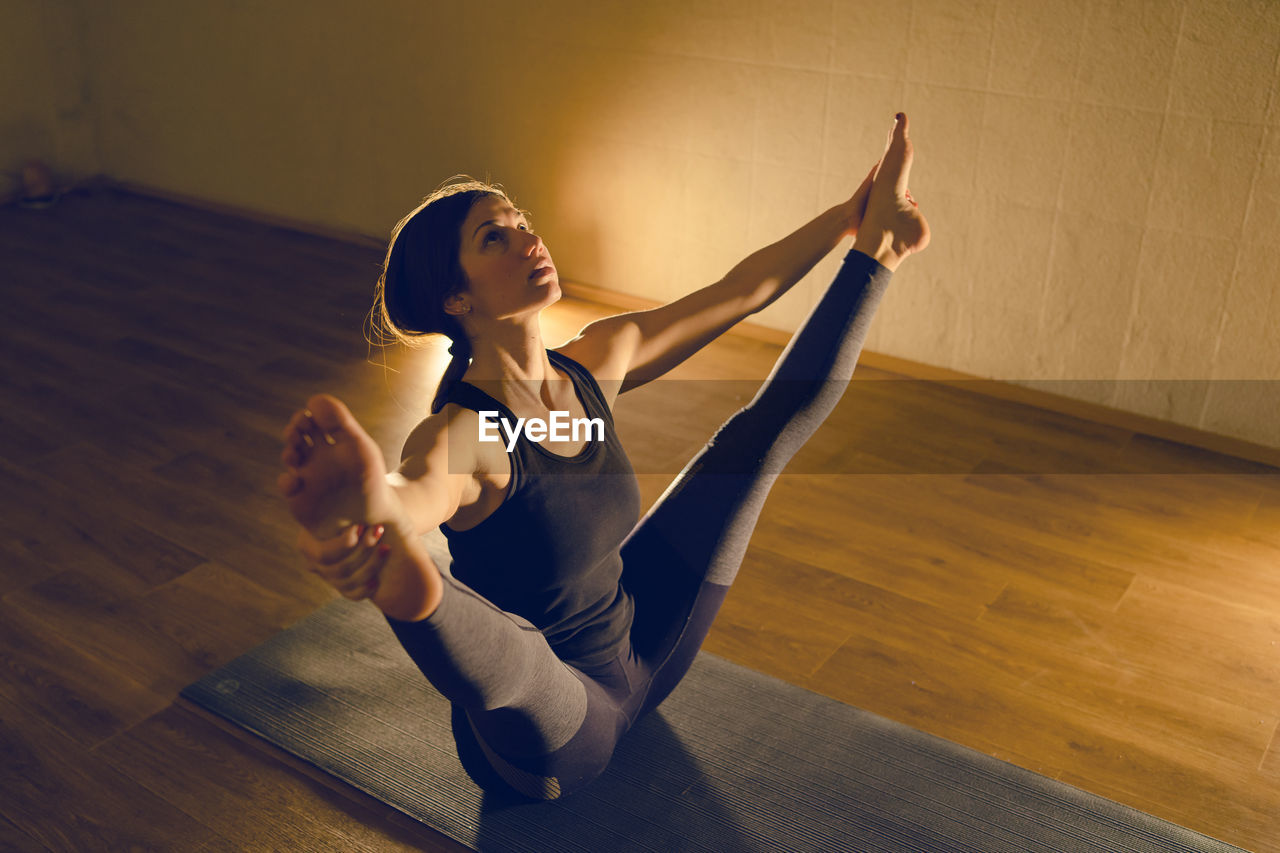 High angle view of woman doing yoga while sitting on floor