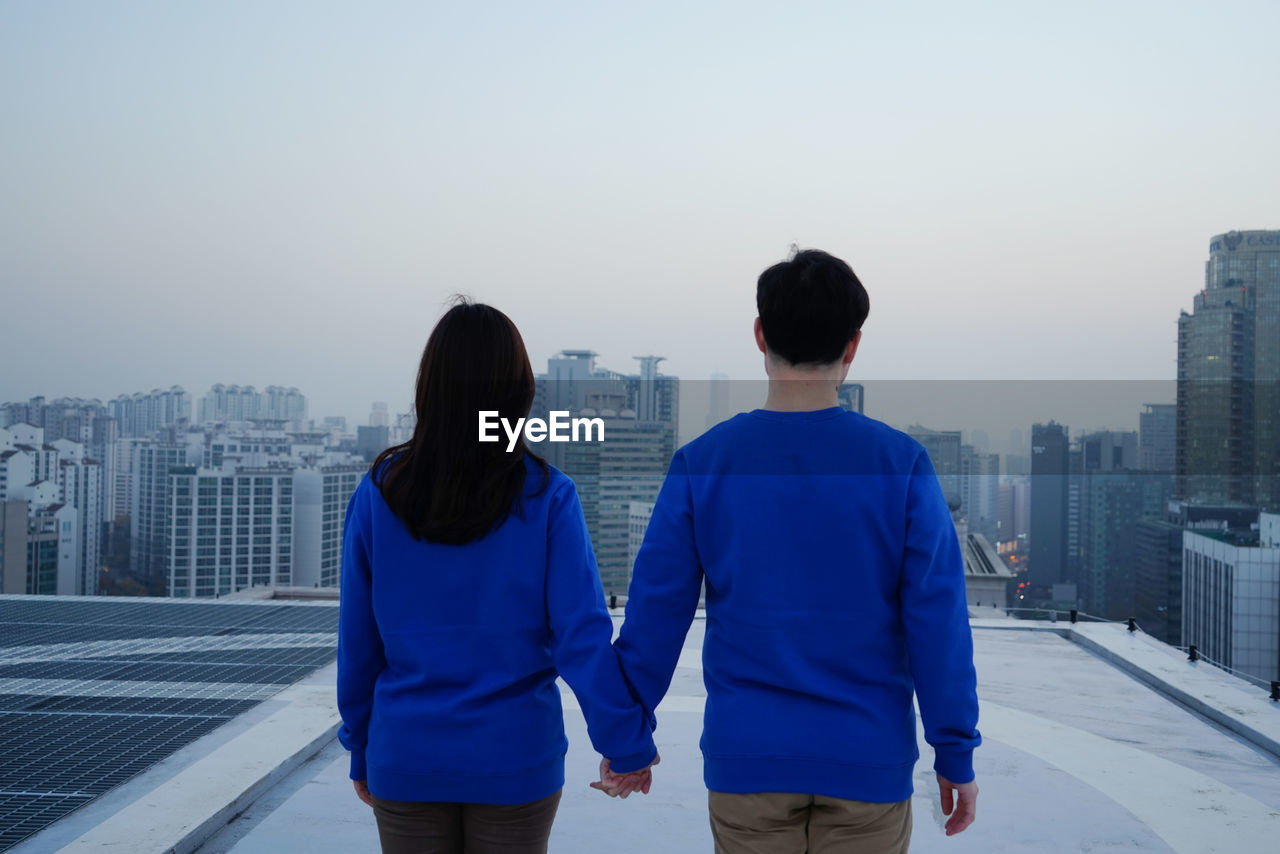 Rear view of man and woman standing against clear sky