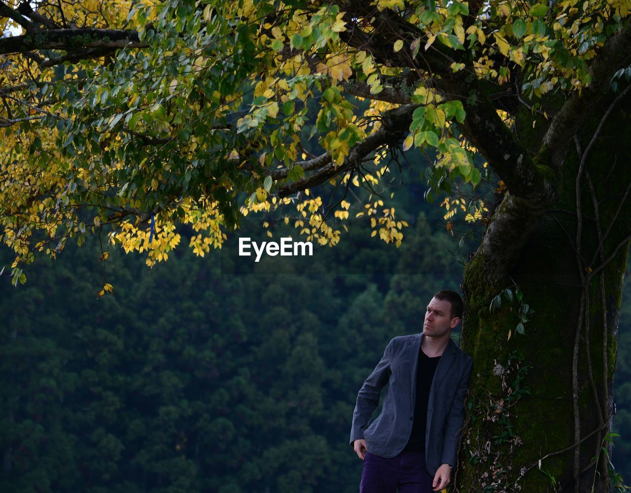 Thoughtful man standing by tree during autumn