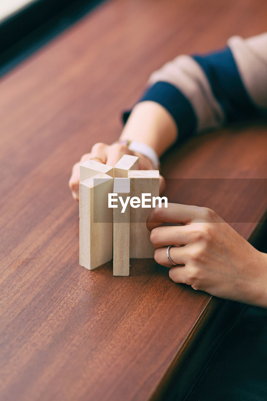 Cropped image of woman hand holding wooden blocks at table