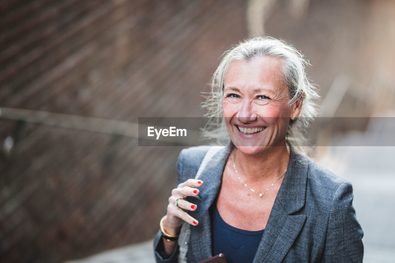 Portrait of happy mature businesswoman standing outdoors