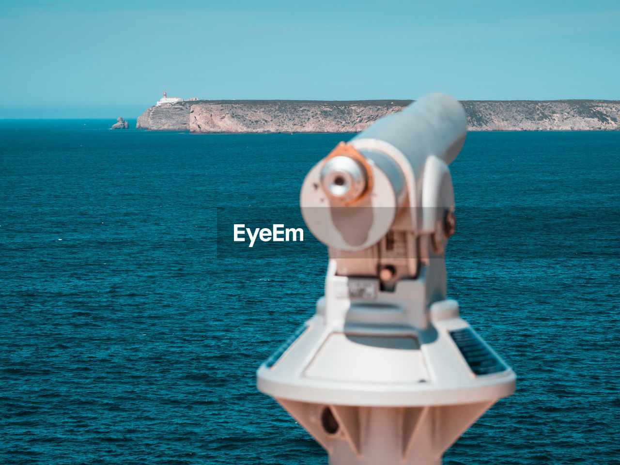 Coin-operated binoculars by sea against clear sky