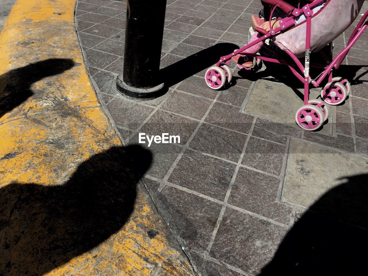 LOW SECTION OF WOMAN WITH SHADOW OF PEOPLE ON TILED FLOOR