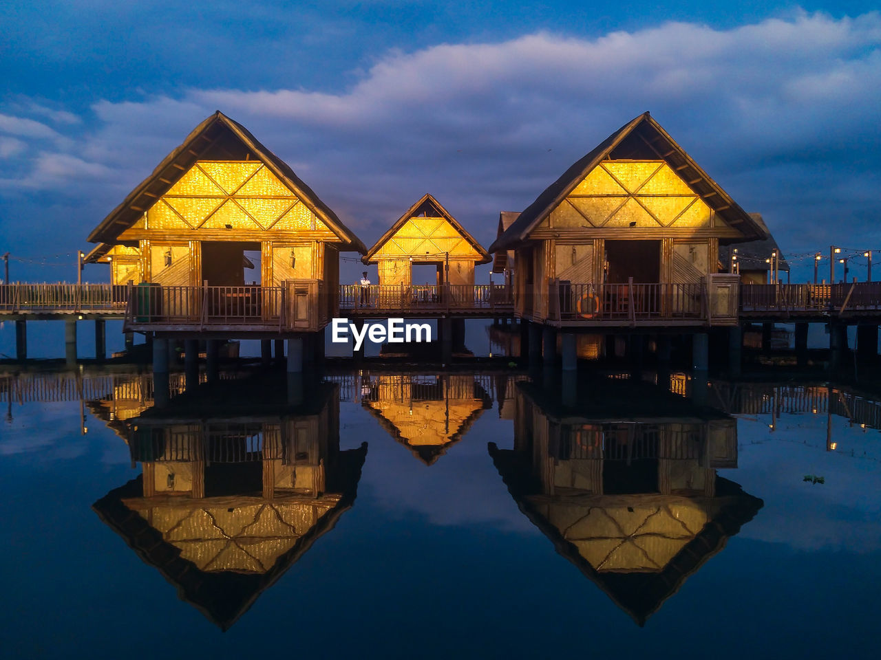 Wooden houses with reflection by laguna lake against sky