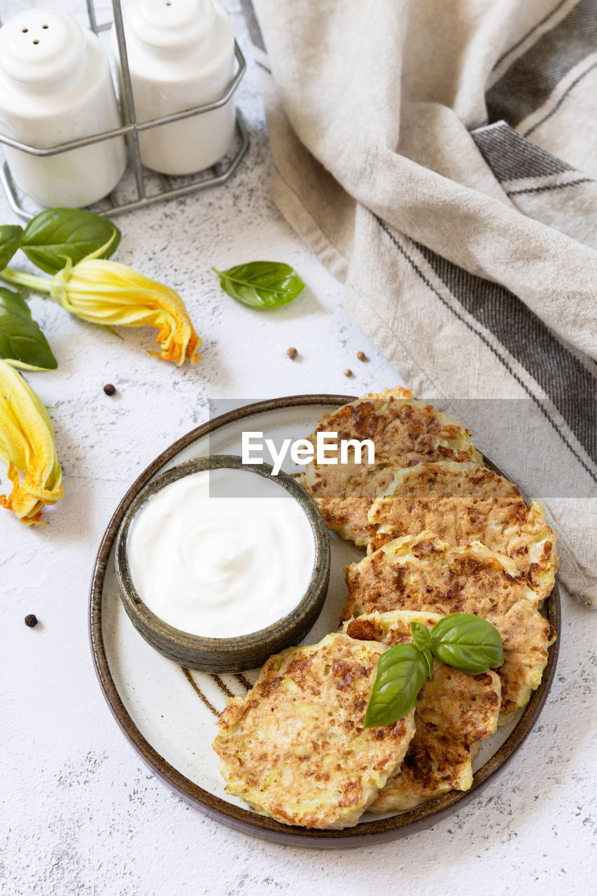 Zucchini fritters. vegetarian zucchini pancakes with cheese, served with sour cream 