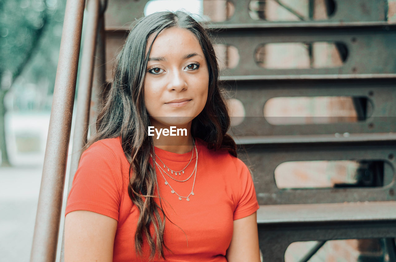 Portrait of smiling young woman sitting on staircase outdoors