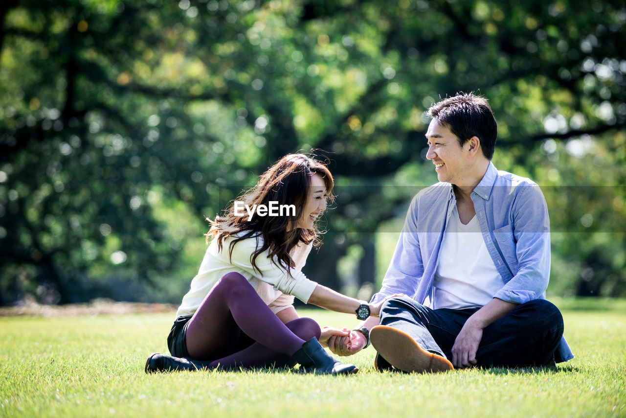 Smiling couple sitting on grass at park