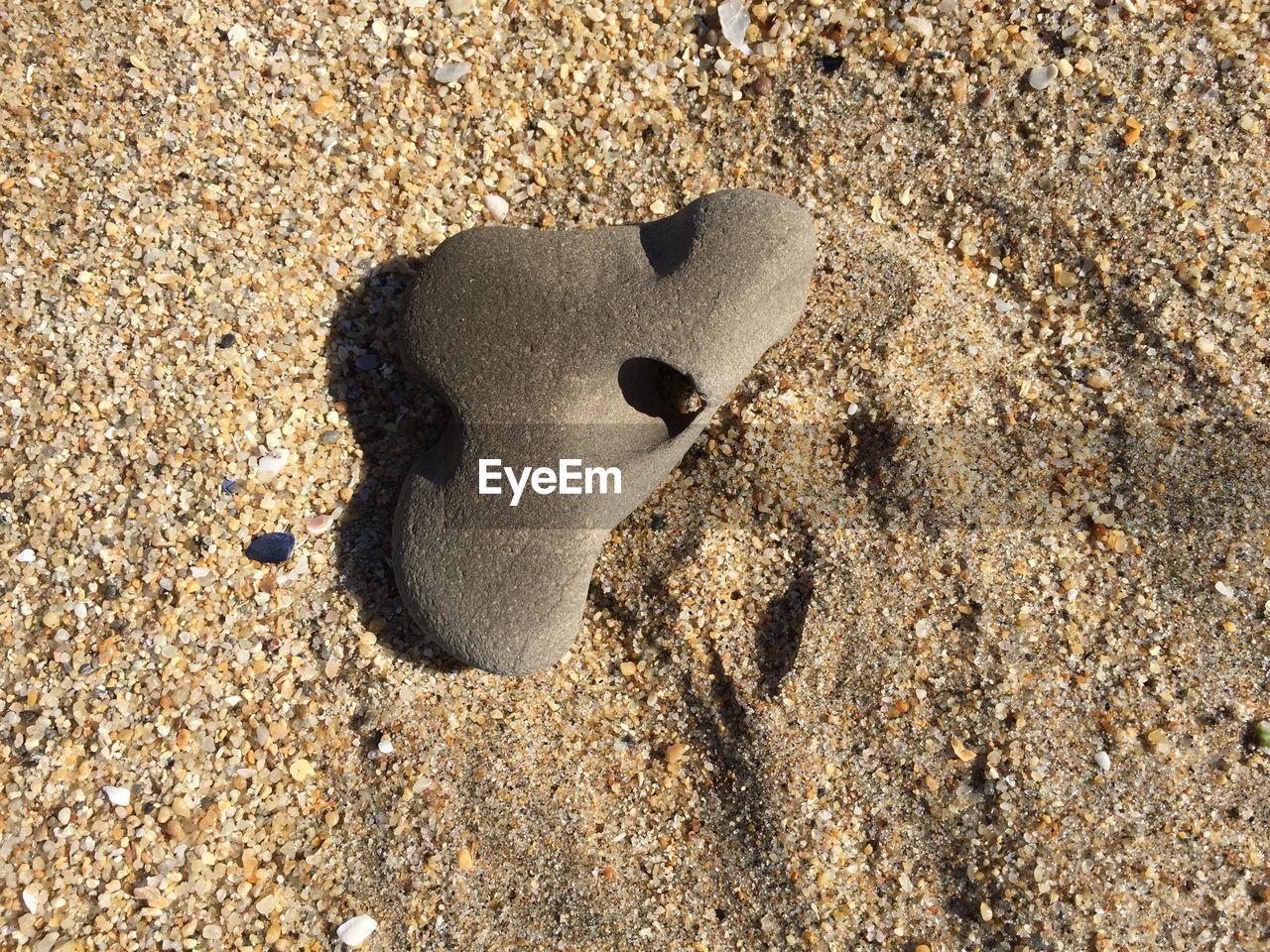 High angle view of stone with hole on beach