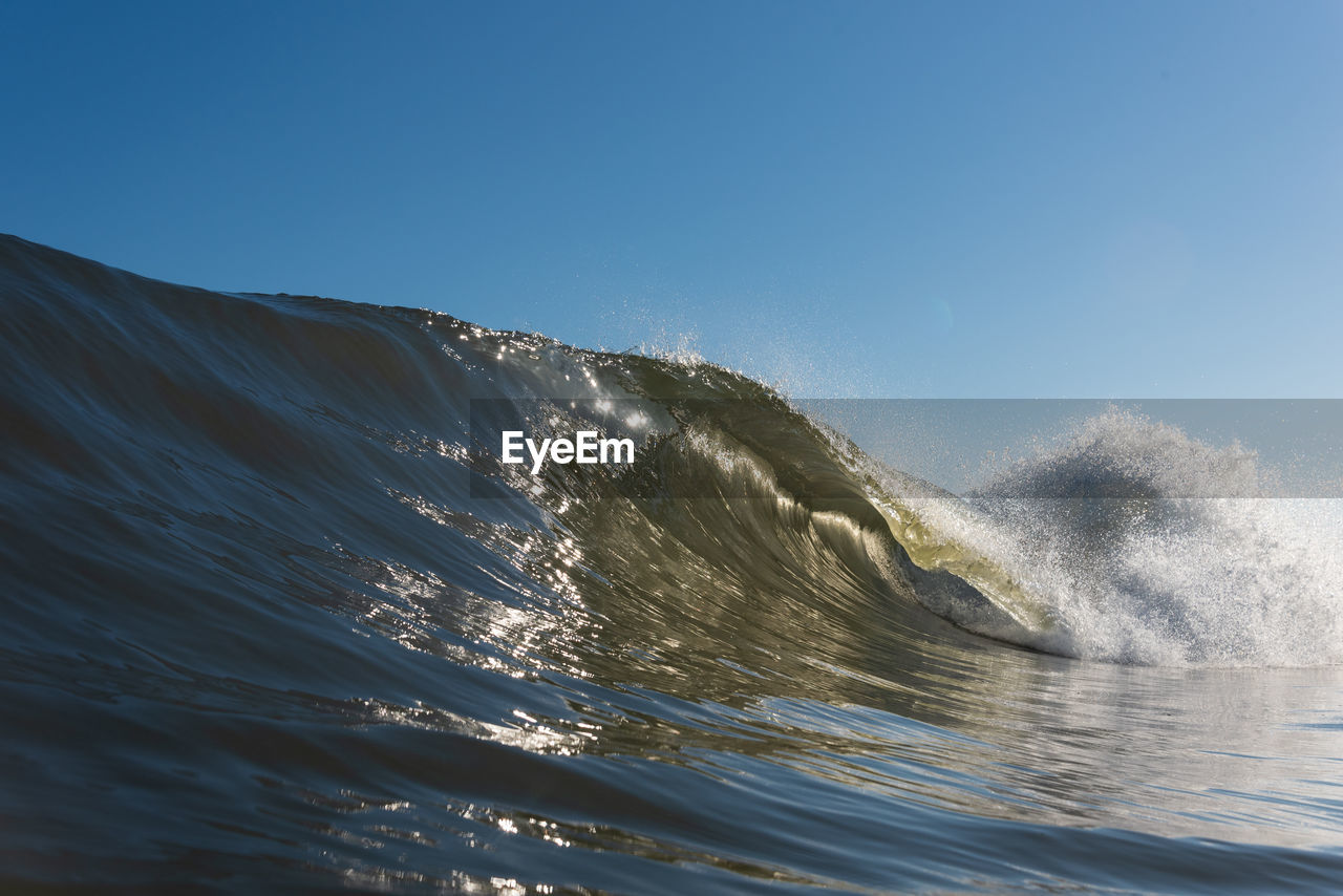 Sea waves splashing against clear blue sky