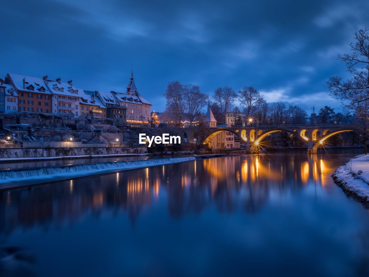 Illuminated bridge over river against sky at night